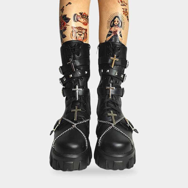 a woman wearing black goth boots customized with chain and crosses