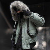 Man wearing a green cargo jacket with fur hood, a black tactical gloves