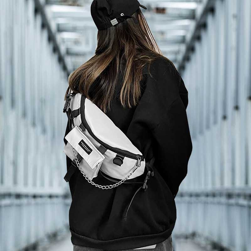 Woman wearing the best techwear sling bag, a black techwear cap and an oversize hoodie