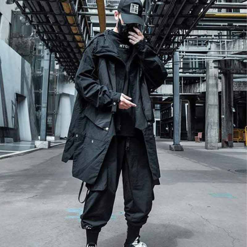 man with a black techwear cap and a black long streetwear jacket