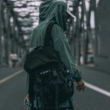 man wearing a black messenger bag and a streetwear hoodie