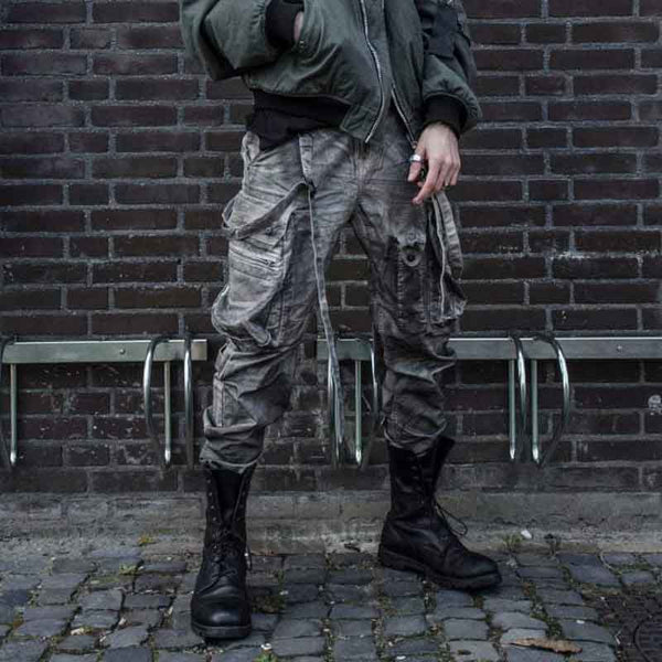 man wearing combat boots techwear with a military cargo pants and an army bomber coat