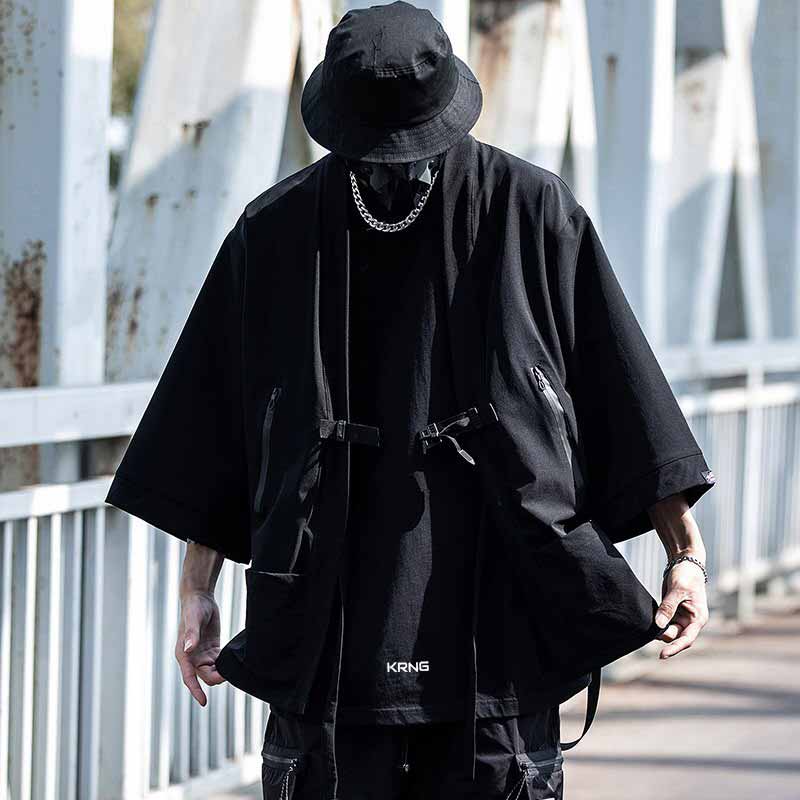 man wearing a black tactical kimono streetwear with a techwear hat and a techwear silver chain