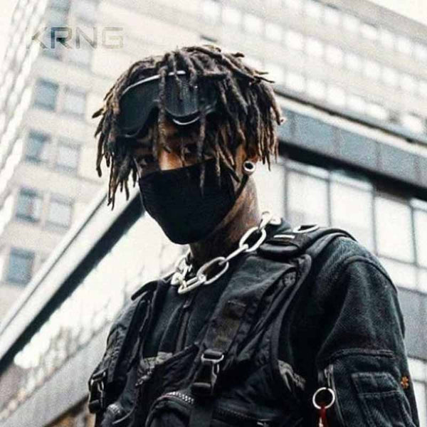 A man wearing Scarlxrd googles are black with techwear aesthetic, a silver chain neck and military tactical vest