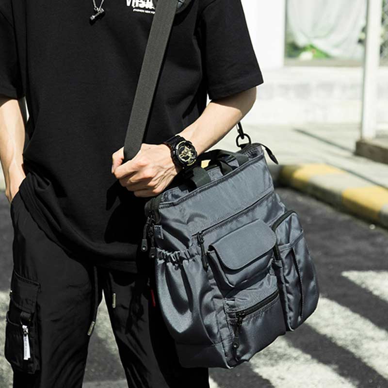 Man with black shirt holding a techwear shoulder bag for laptop